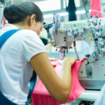 Asian Seamstress or worker in an Asian textile factory sewing with a industrial sewing machine, she is very accurate